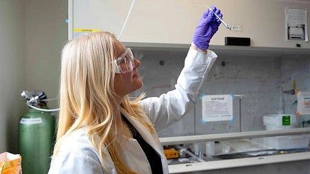 a woman holding a test tube in a lab